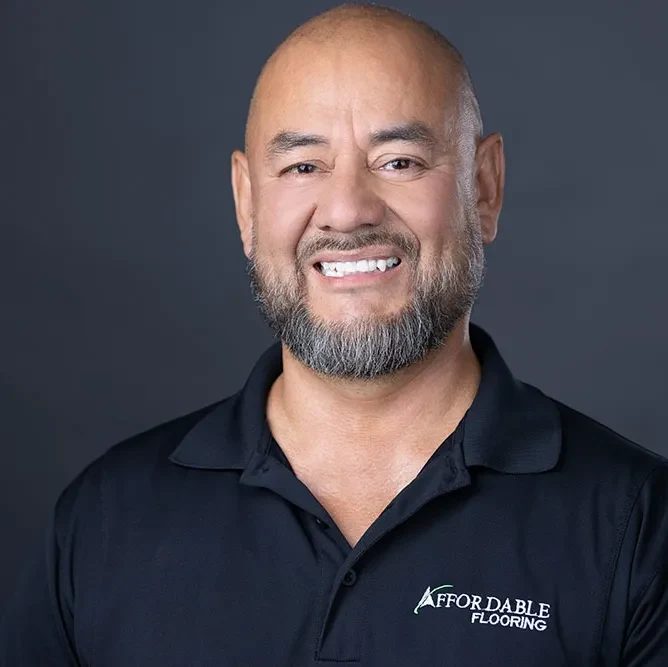 Alberto Gomez, Field Supervisor at Affordable Flooring & More, in a company polo against a grey studio backdrop