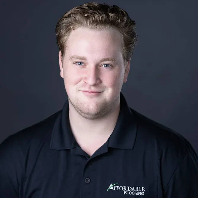 Braedon Buchanan, Warehouse Associate at Affordable Flooring & More, in a company polo against a grey studio backdrop